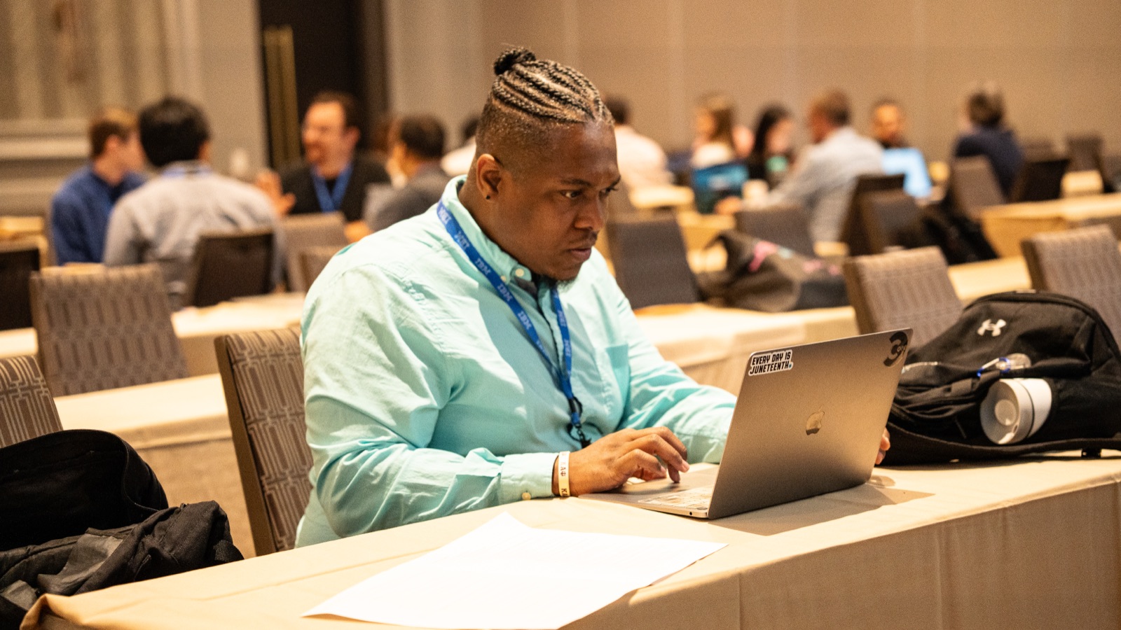 Cordero working intently on a laptop between sessions in a conference hall